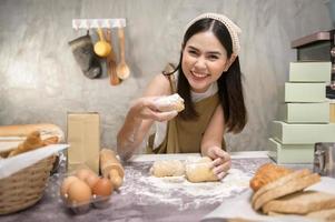 jovem mulher bonita está assando em seu negócio de cozinha, padaria e cafeteria foto