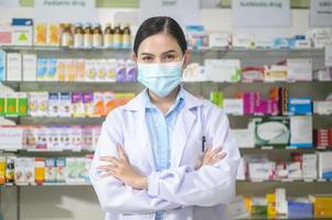 retrato de farmacêutico feminino usando máscara facial em uma farmácia de farmácia moderna. foto