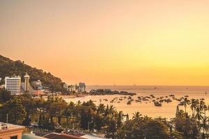 vista aérea da cidade de vung tau com belo pôr do sol e tantos barcos. vista panorâmica do litoral vung tau de cima, com ondas, litoral, ruas, coqueiros e montanha tao phung no vietnã. foto