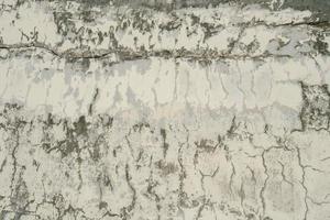 textura do velho muro de concreto cinza para segundo plano. textura áspera na parede cinza forma áspera devido à camada de tinta descascada devido à chuva. foto