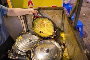 crepes vietnamitas banh xeo recheados com carne de porco ou frango também, camarão, cebola e broto de feijão e molho picante colocado perto do prato na mesa foto