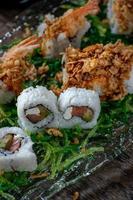 sushi com atum e camarão na cama de salada de algas verdes foto