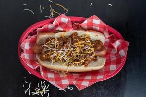 cachorro de pimenta com cebola e queijo em um pão plano lay foto