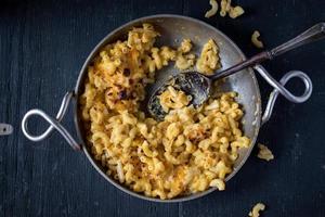 macarrão de queijo e macarrão no prato com colher em local vazio postura plana foto