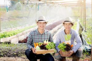 belo retrato jovem dois homens colheita e pegando horta orgânica fresca na cesta na fazenda hidropônica, agricultura para alimentação saudável e conceito de empresário de negócios. foto