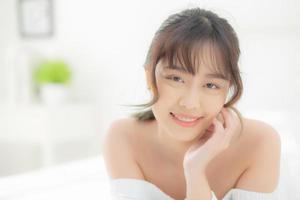 belo retrato jovem asiática deitada e sorrir enquanto acorda com o nascer do sol de manhã, beleza linda garota feliz e alegre descansando na cama no quarto, estilo de vida e conceito de relaxamento. foto