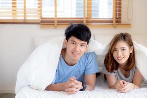 belo retrato jovem casal asiático relaxa e satisfeito juntos no quarto em casa, família deitada na cama confiante com alegre e feliz com relacionamento, namoro de homem e mulher. foto