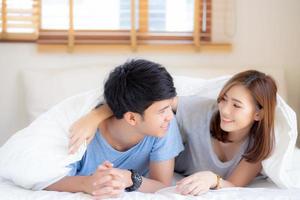 belo retrato jovem casal asiático relaxa e satisfeito juntos no quarto em casa, família deitada na cama confiante com alegre e feliz com relacionamento, namoro de homem e mulher. foto