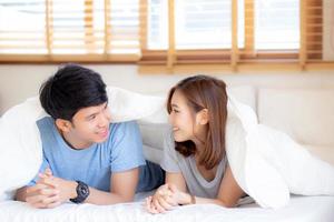 belo retrato jovem casal asiático relaxa e satisfeito juntos no quarto em casa, família deitada na cama confiante com alegre e feliz com relacionamento, namoro de homem e mulher. foto