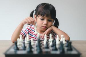 menina asiática jogando xadrez em casa. um jogo de xadrez foto