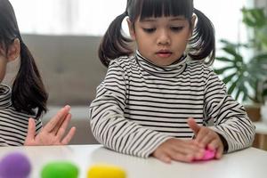 a menina está aprendendo a usar massinha colorida em uma sala bem iluminada foto