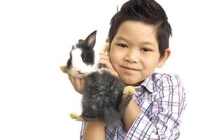 criança asiática brincando com lindo coelho bebê isolado sobre o branco foto