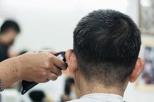 homem corta o cabelo na barbearia - pessoas no conceito de salão de beleza de cabeleireiro foto