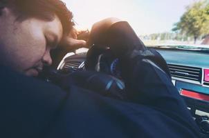 homem dorme no carro enquanto dirige na estrada - pessoas tentaram de longa viagem e conceito de tráfego foto