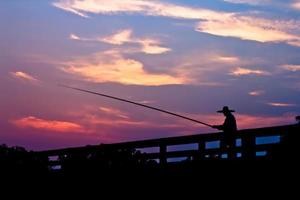 homem pescando no pôr do sol.