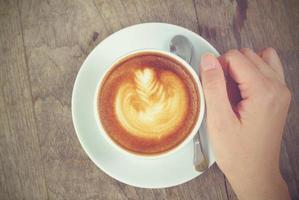 mãos de mulher segurando latte art, xícara de café com tom vintage foto