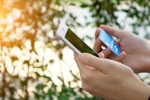 mãos de mulher segurando cartão de crédito e usando telefone inteligente. compras online foto