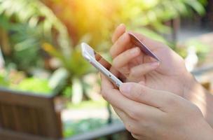 mãos de mulher segurando cartão de crédito e usando telefone inteligente. compras online foto