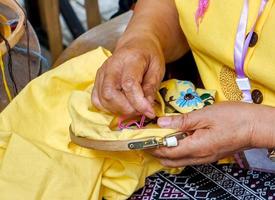 mãos closeup de senhoras estão demonstrando costura e decoração de roupas por bastidor para alunos na aula de trabalho doméstico. foto