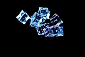 cubos de gelo em um fundo preto. gelo caindo em um fundo preto para uso como ilustração em um projeto foto