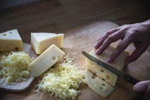 mulher preparando queijo para cozinhar usando ralador de queijo na cozinha - pessoas fazendo comida com conceito de queijo foto