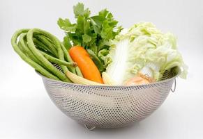 vários tipos de legumes na cesta de alumínio em fundo branco. foto