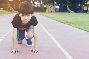 menino de escola saudável pronto para correr no ponto de partida, conceito de competição ativa foto