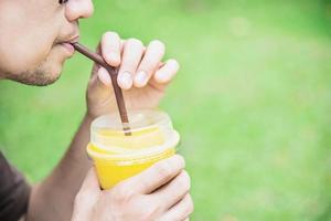 homem bebe gelo manga laranja mistura no jardim verde - relaxe as pessoas com o conceito de bebida de frutas frias foto