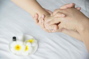 massagem de spa de mão sobre fundo de cama branca limpa - as pessoas relaxam com serviço de massagem de mão foto