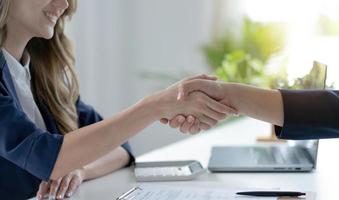 closeup de empresária feliz irreconhecível apertando as mãos com o parceiro de negócios após a assinatura do contrato durante a reunião no escritório. foto