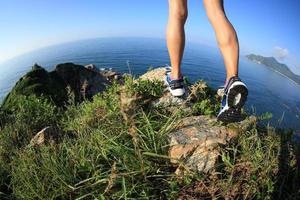 pernas de mulher alpinista caminhadas no pico da montanha à beira-mar