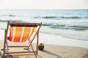 relaxe a cadeira de praia com abacaxi de coco e copo de coquetel na praia de areia limpa com mar azul e céu claro - fundo da natureza do mar relaxe o conceito foto