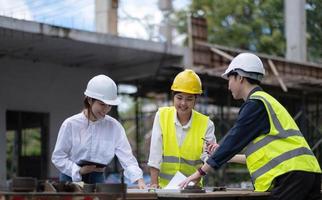 três especialistas inspecionam locais de construção de edifícios comerciais, edifícios industriais projetos imobiliários com engenheiros civis, investidores usam laptops em casa de fundo, enquadramento de cofragem de concreto. foto