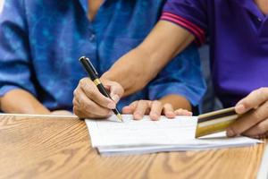 idosos asiáticos segurando caneta contrato pagamento seguro cartão de crédito papelada de cuidados de saúde ou relatório de documento conceito de finanças de compras. foto