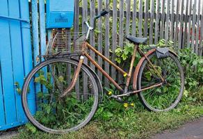 bicicleta velha pela cerca de madeira foto