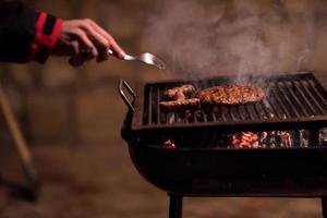 jovem cozinhando carne no churrasco foto