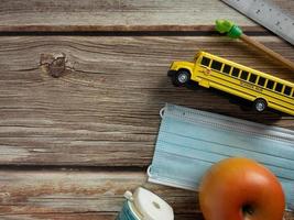 ônibus escolar e máscara na mesa de madeira para educação ou conceito médico foto