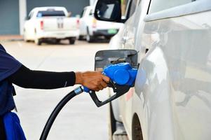 mão segurando o bocal de diesel azul no posto de gasolina, o conceito de crise do petróleo, óleo caro foto