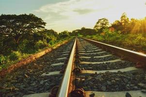 os trilhos do trem noturnos estavam iluminados pelo sol amarelo que brilhava forte. foto