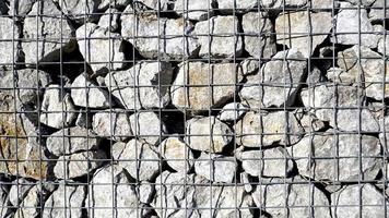 quadro cheio de gabião com pedras grossas, cesta de pedra metálica cheia de fundo de textura de grandes pedras naturais foto