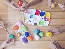 pessoas pintando ovos de páscoa coloridos - conceito de celebração do feriado de páscoa foto