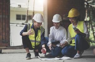 construção profissional e equipe de engenheiros trabalhando no local de trabalho. arquiteto negro profissional e trabalhador da construção civil trabalhando olham para o plano de planta no local. foto