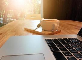 xícara de café e laptop na mesa de madeira na cafeteria. conceito de negócios foto