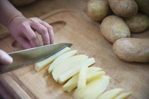 pessoas cozinhando batata fresca preparando comida na cozinha - conceito de cozimento de batata foto