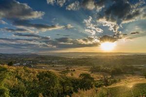 pôr do sol atrás da montanha. flor, árvore e grama foto