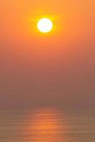 pôr do sol, a superfície do mar, refletindo o sol em laranja. céu claro, laranja sem nuvens foto