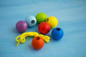 brinquedo infantil de desenvolvimento. bolas de madeira coloridas em uma corda. miçangas de madeira coloridas para colar. foto