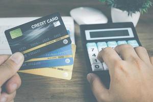 tecnologia de compras online conceito masculino mão segurando o cartão de crédito para calcular o custo e fazer compras online. foto