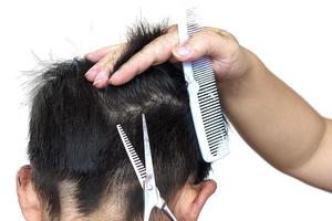 um menino é cortado o cabelo pelo cabeleireiro isolado sobre fundo branco foto