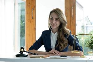 retrato, atraente e encantadora jovem empresária asiática ou gerente executiva feminina senta-se em sua mesa de escritório na moderna sala de escritório brilhante. foto